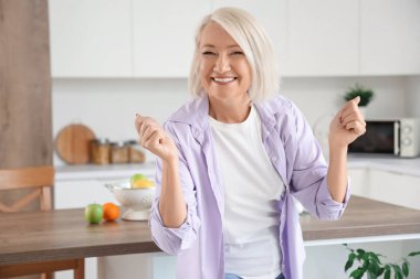 Mutfakta dans eden olgun bir kadın.