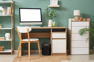 Modern bilgisayar, taşınabilir güç istasyonu ve mavi duvara yakın bambu gövdeleri olan rahat çalışma alanı