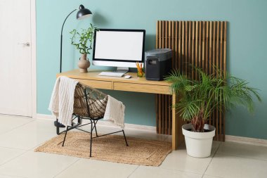 Modern bilgisayarlı rahat çalışma alanı, taşınabilir elektrik santrali ve mavi duvarın yanındaki tesisler.