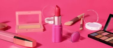 Pembe arka planda ruj ve farklı kozmetik ürünler.