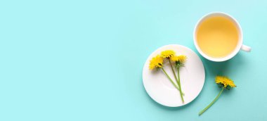 Bir fincan sağlıklı karahindiba çayı ve çay tabağı açık mavi arkaplanda ve metin için yer var. 