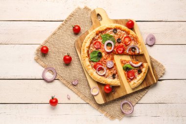 Beyaz ahşap arka planda fesleğenli ve domatesli lezzetli pizza.