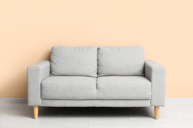 Bej duvarın yanındaki rahat gri kanepe