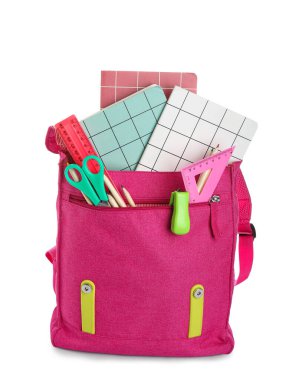 Beyaz arka planda farklı kırtasiye malzemeleriyle süslü pembe okul çantası.