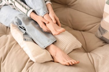 Genç bir kadın kanepeye ayak masajı yapıyor.