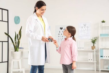 Female ophthalmologist with trial frame and little girl in clinic
