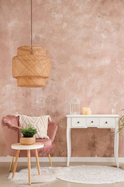 Pembe koltuğu ve bej duvarın yanında tuvalet masası olan şık bir oturma odası.