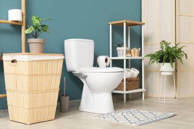 Tuvalet, çöp tenekesi, merdiven ve raf ünitesi mavi duvarın yanında.