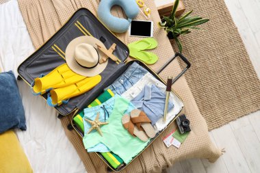 İçinde giysiler, plaj aksesuarları, dürbün ve yatak odasındaki kamera olan valizi aç.