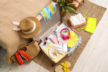 İçinde giysiler, plaj aksesuarları, kulaklıklar, cep telefonları ve pasaport olan valizi yatak odasının yanında, en üst katta.