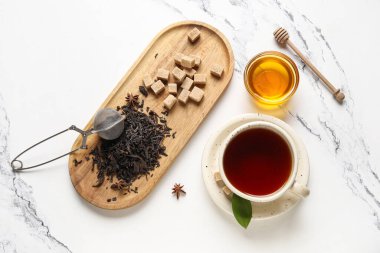 Bir fincan sıcak siyah çay ve beyaz arka planda kuru yapraklı ahşap tepsi.