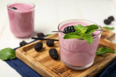 Beyaz ahşap arka planda naneli taze böğürtlen smoothie bardakları, yakın plan