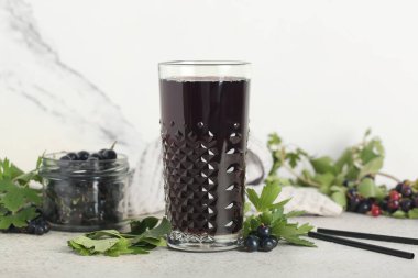Beyaz arka planda böğürtlenli taze siyah frenk üzümü suyu ve kavanozu.