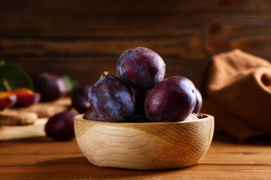 Ahşap arka plan üzerinde taze olgun Erik ile kase