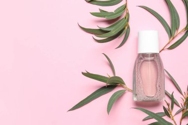 Pembe arka planda bitki dalları olan bir şişe mikiler suyu.