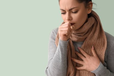 Yeşil arka planda öksüren hasta genç kadın, yakın plan.