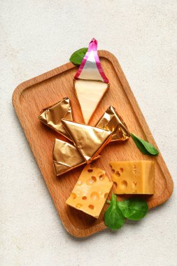 Lezzetli işlenmiş üçgen ve açık arkaplanda İsviçre peyniri olan ahşap tahta tahta.