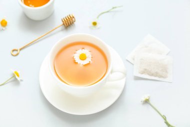 Ballı sıcak çay ve soluk mavi arka planda çiçekler.