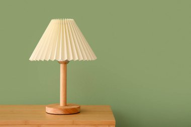 Lamba, yeşil duvarın yanındaki ahşap masada.