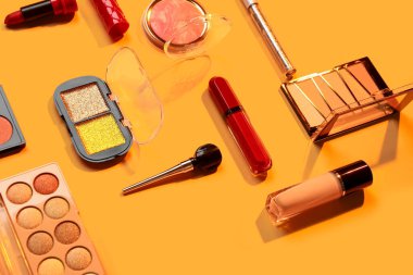 Güzel göz falı paletleri ve turuncu arka planda farklı dekoratif kozmetikler.