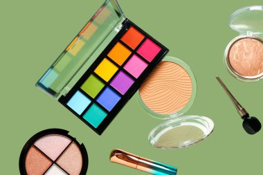 Yeşil arka planda uçan dekoratif kozmetik ürünleri