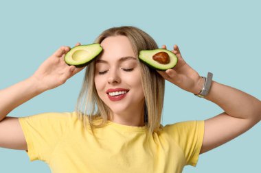Mavi arka planda avokadosu olan genç bir kadın.