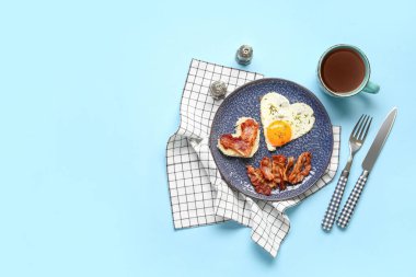 Composition with tasty bacon, fried egg, bread and cup of tea on blue background