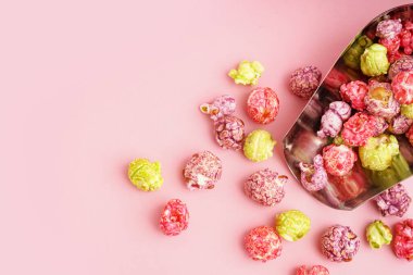 Pembe arka planda tatlı patlamış mısırlı metal kepçesi