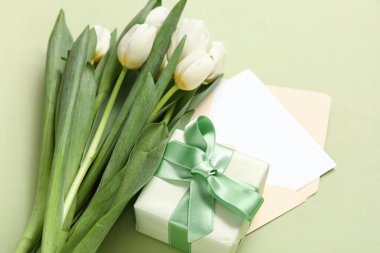 İçinde boş kart, hediye kutusu ve yeşil arka planda beyaz laleler olan zarf.