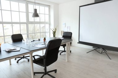 Masa ve projektör ekranlı ofis içi toplantı için hazırlandı