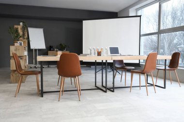 Masası, ekranı ve koltukları olan modern bir konferans salonu.