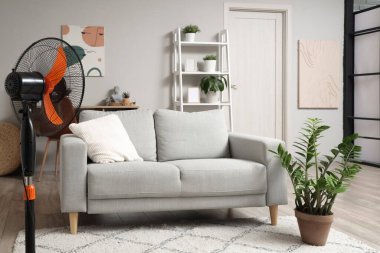 Evde elektrikli vantilatör ve şık bir kanepe var.