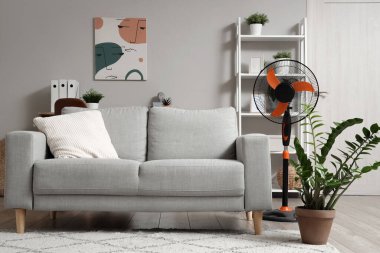 Evde elektrikli vantilatör ve şık bir kanepe var.