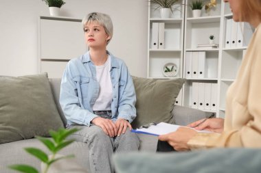 Üzgün genç kız psikologun ofisinde kanepede oturuyor.