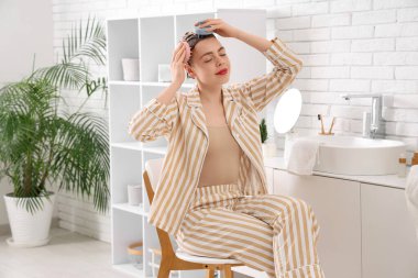 Banyoda saç derisi masajı yapan genç bir kadın.