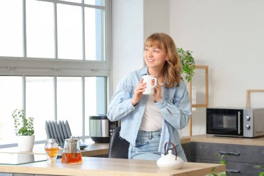 Mutfakta çay içen bir kadın.