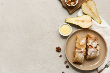 Lezzetli armutlu börek tabağı, fındık ve gri arka planda taze kesilmiş meyve.