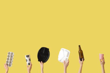 Sarı arka planda çöpleri olan kadın eller. Geri dönüşüm kavramı