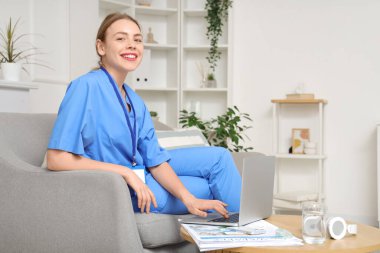 Genç bayan tıp öğrencisi modern bilgisayarla evde çalışıyor.