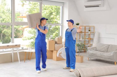 Yükleyiciler şık bir odada sandalye ve puf taşıyor.