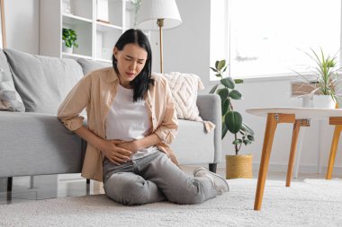 Evde şiddetli karın ağrısı çeken genç bir kadın var.