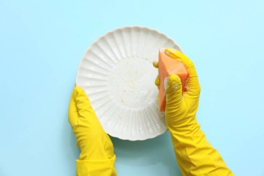 Eller mavi arka planda bulaşıkları yıkıyor.