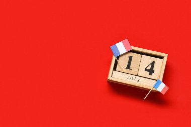 14 Temmuz tarihli küp takvimi ve kırmızı arka planda Fransız bayrakları. Bastille Günü kutlamaları