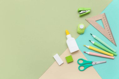 Keçeli kalemli bir şişe yapıştırıcı ve renkli arka planda zımba. Üst görünüm