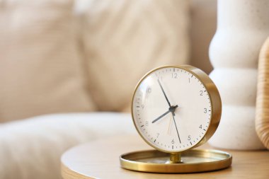 Odadaki sehpanın üzerinde vazo ve çerçeveli altın çalar saat. Yakın çekim.