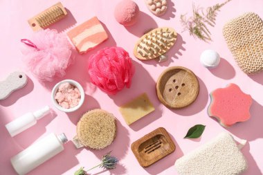 Kozmetik ürünleri ve pembe arka planda farklı banyo malzemeleri içeren kompozisyon