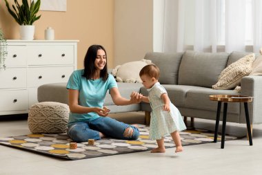 Küçük kız, annesi ve küpüyle yürümeyi öğreniyor.