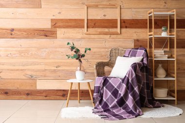 Sehpalı sehpa ve mor ekose hasır koltukta, odasındaki tahta duvarın yanında.