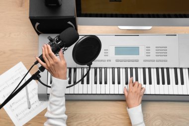 Kayıt stüdyosunda mikrofonlu kadın eller sentezleyici çalıyor.