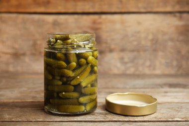 Ahşap arka planda lezzetli salatalıklı kavanoz.